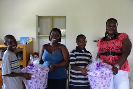 (L-R) Master Austin Bart and his Mother Ms. Shana Phillip’s along with Master Keijarie Huggins and his Mother Ms. Predencia Huggins share a happy moment with the gift of school supplies presented to the students by the Department of Social Services Single Parent Support Group